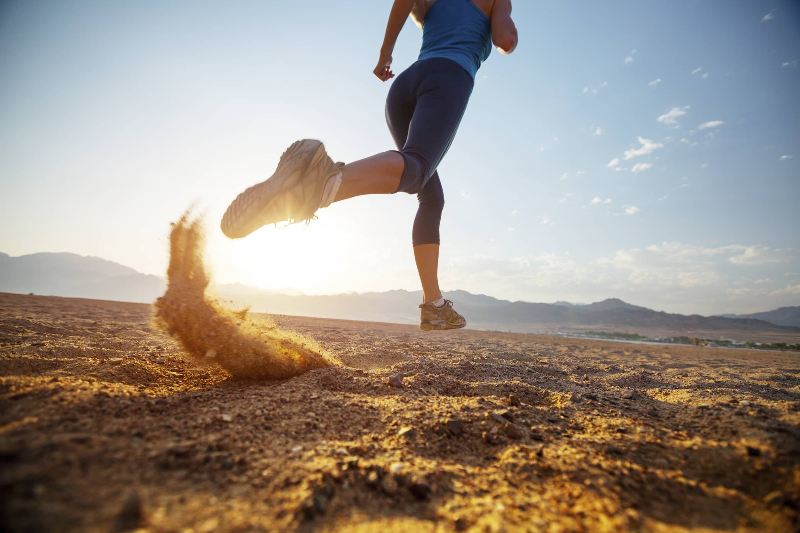 A woman running in the desert on a bright day.