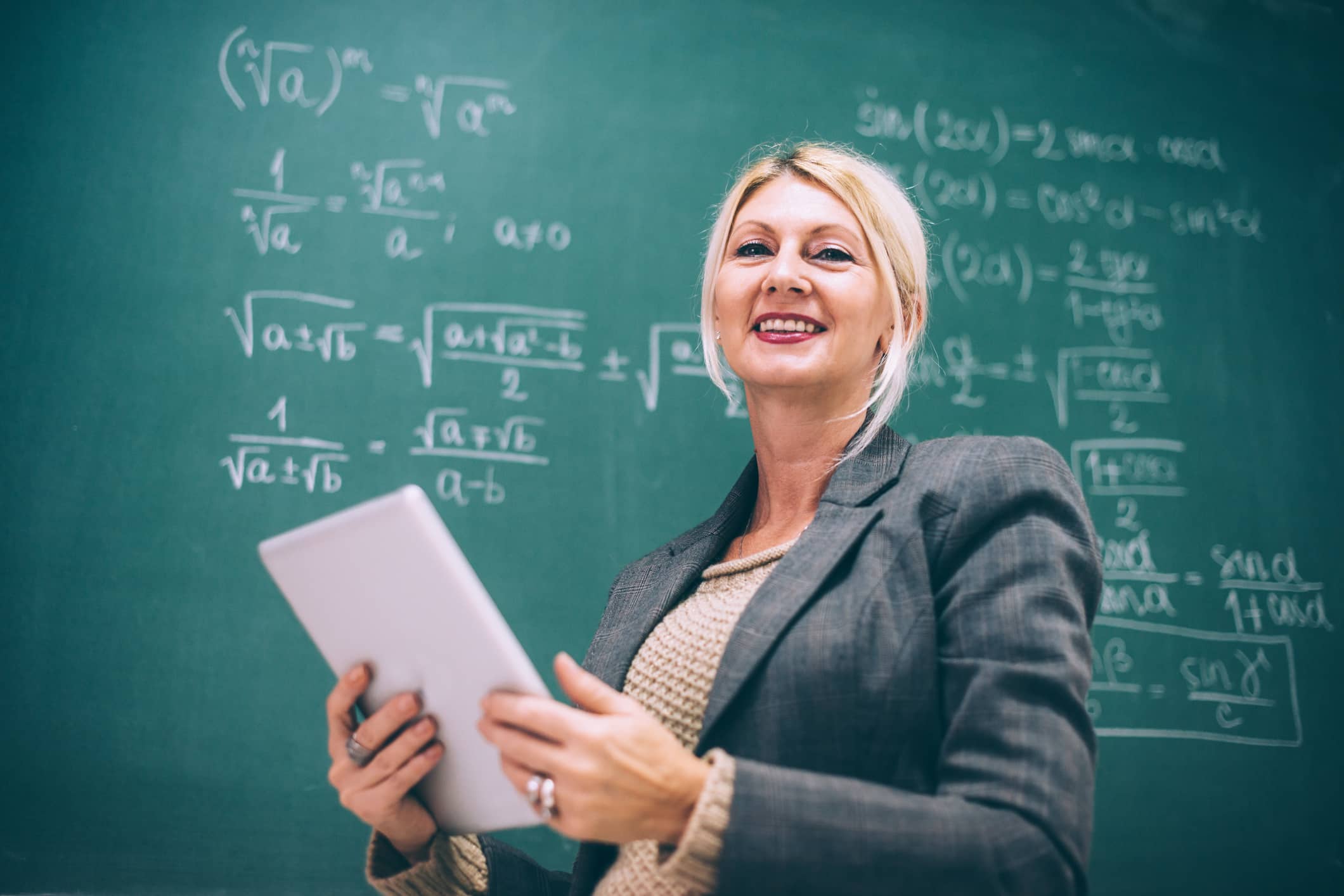 A female teacher teaching a science and technology concept on a chalkboard in the classroom.