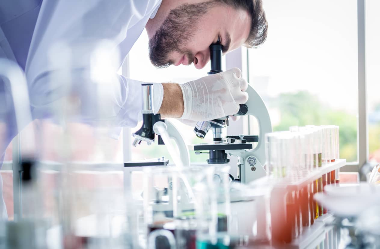 Male scientist looking into a microscope in a lab.