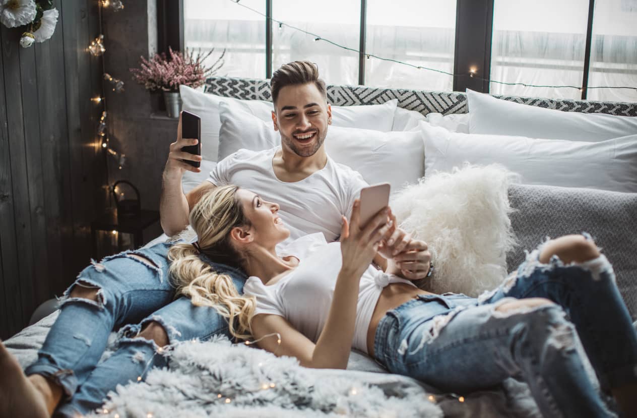 Couple in love lounging together on a bed.