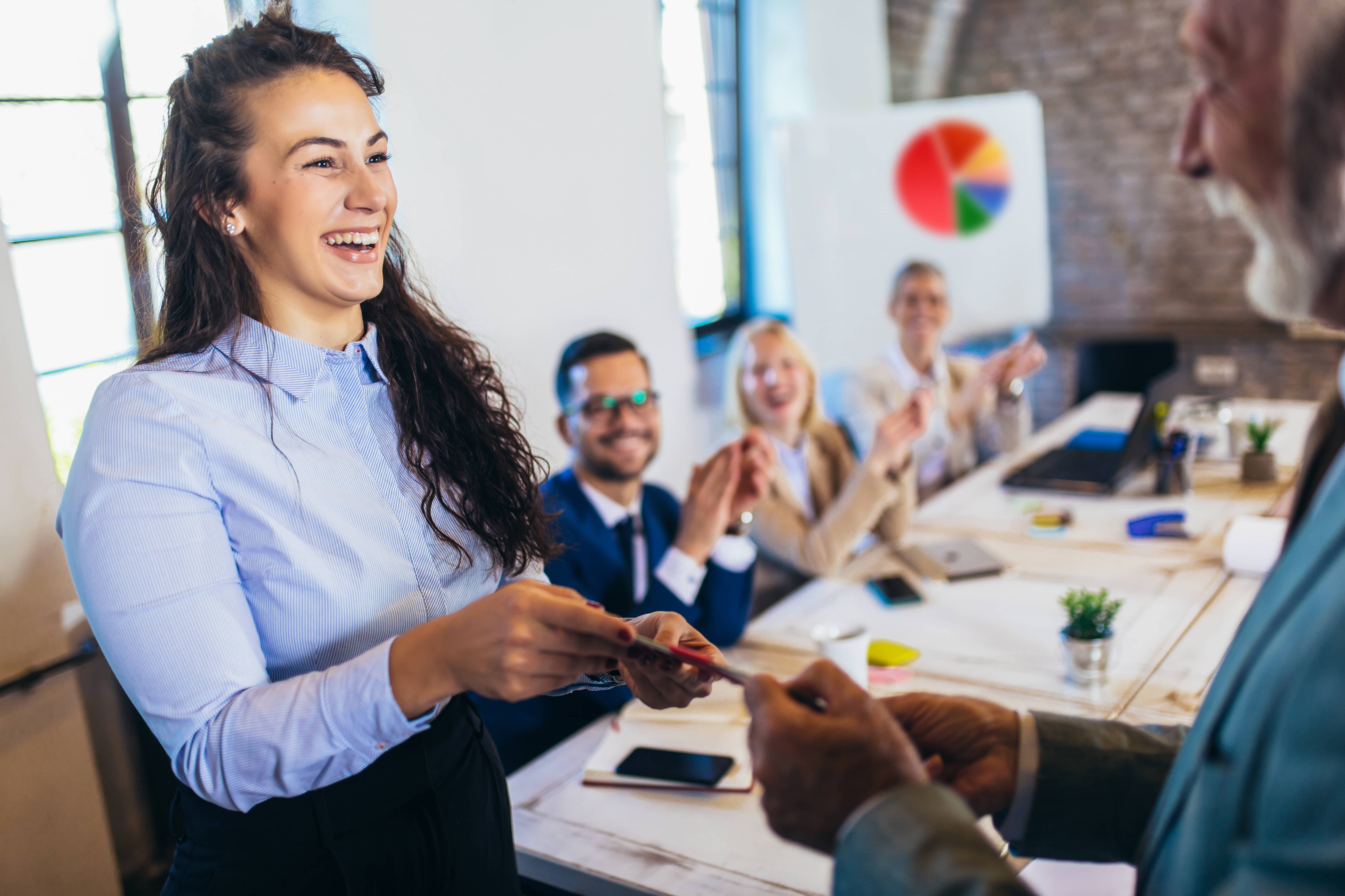 Smiling woman accepting an award at work; celebrating accomplishments encourages extrinsic motivation.