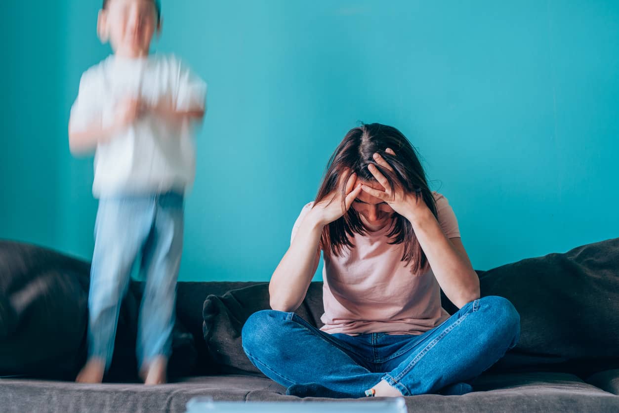 A stressed mom with a boy acting out. She stooped over her arms and feeling like a bad mom.