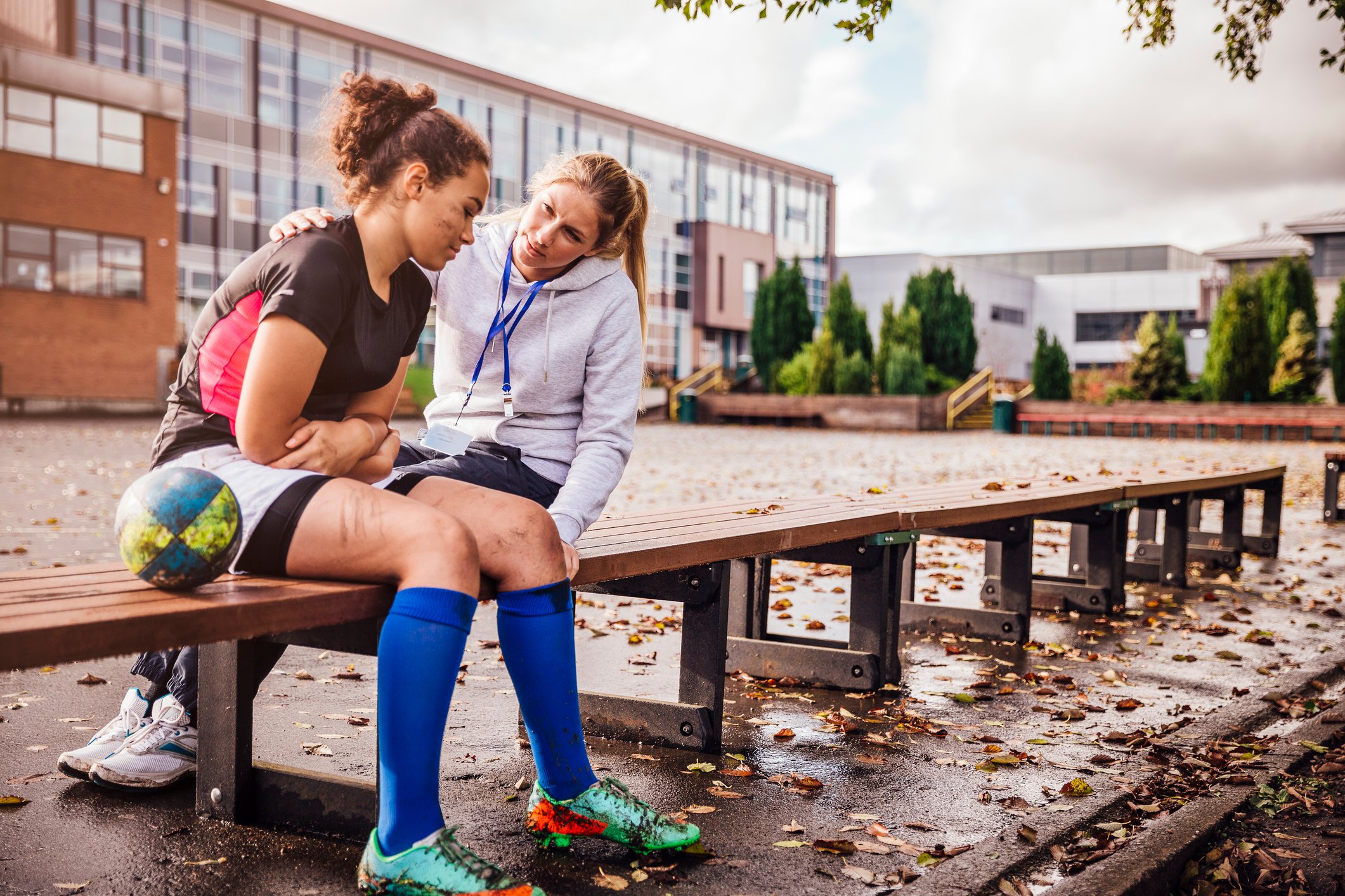 A teacher consoles a teenage girl who lost a soccer game