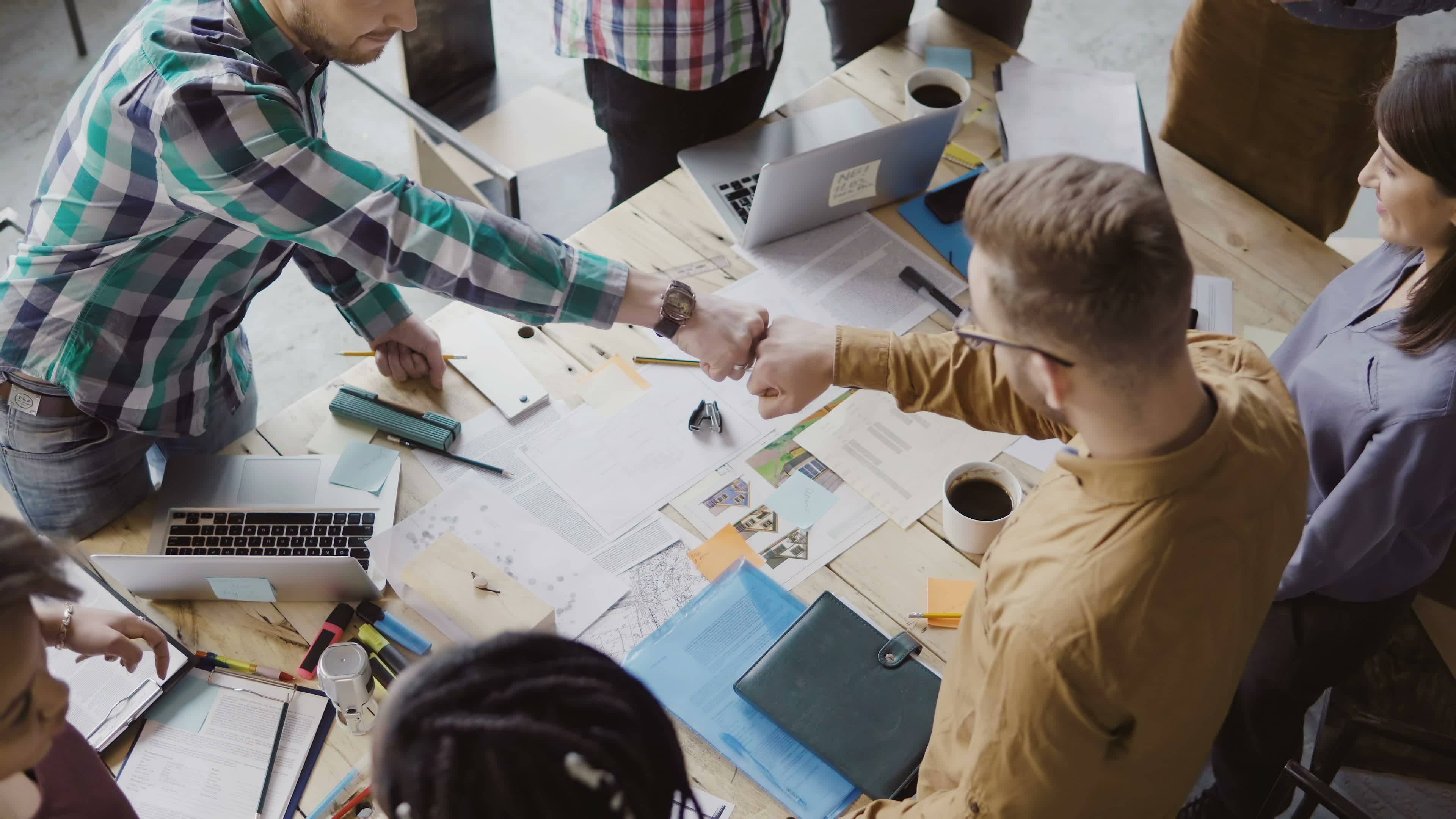 Team with two men knuckle-punch; emotional intelligence increases unity and cooperation.