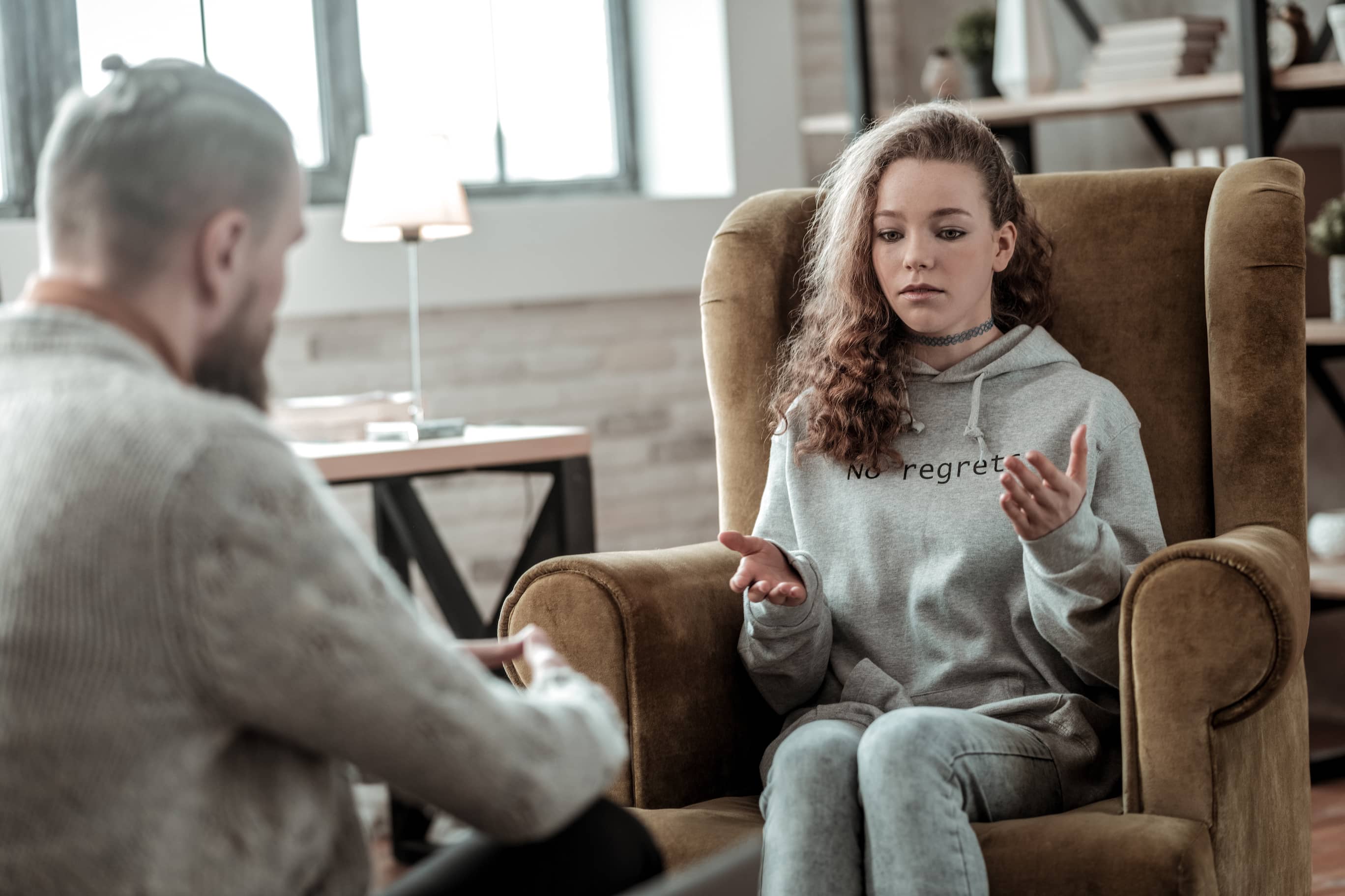 Teen girl earnestly expressing her perspective with her father during a heartfelt conversation in their living room.
