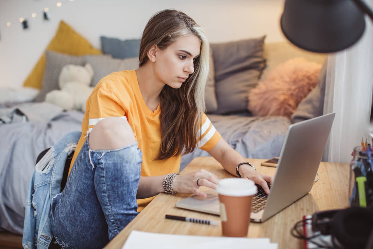 A teenage girl working on a computer in her bedroom.
