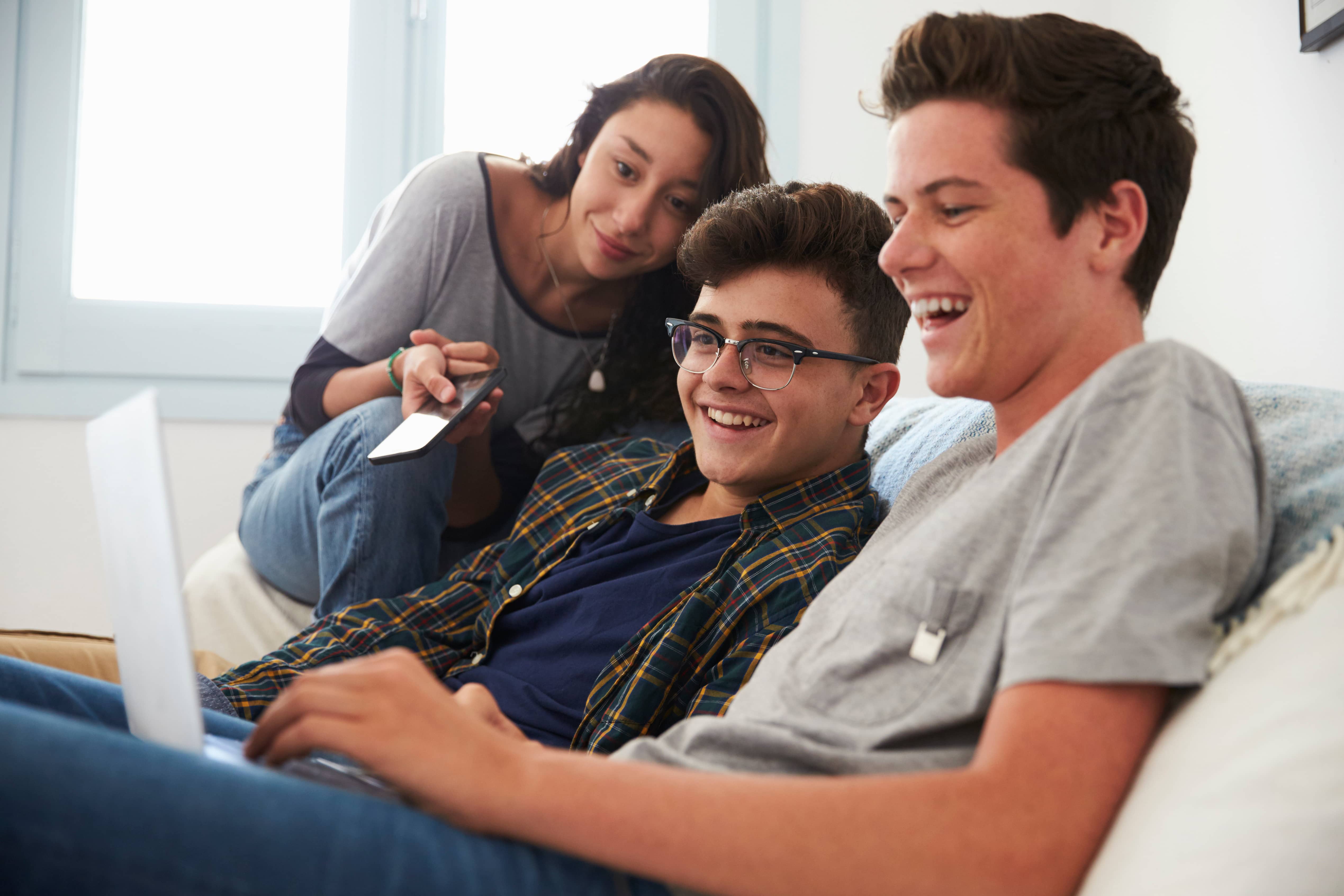 Teenage friends watching something funny on a laptop.