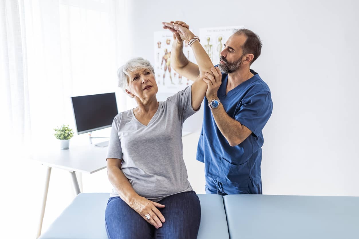 A physical therapist working with an older woman with shoulder pain. -your-pain-lies-in-your-back