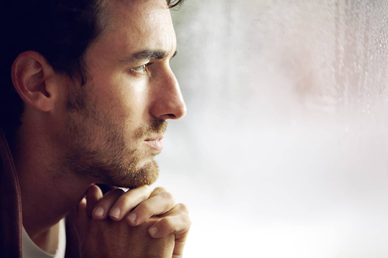 A young bearded man staring out the window trying to self-regulate and calm himself 