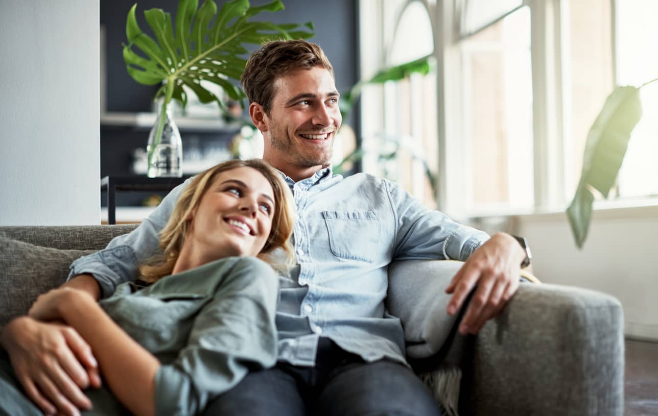 A couple cuddled up on the couch. This connection is what a weekend can look like.