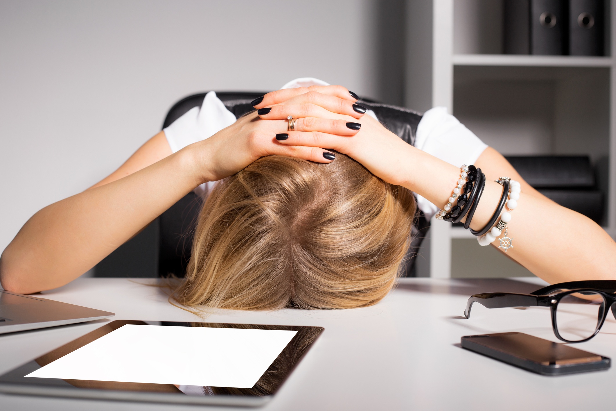 Tired and overwhelmed business woman resting her head on her desk
