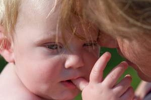 A toddler teething and chewing on her thumb