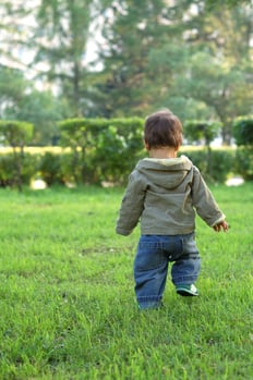 Feisty toddler running across a lawn