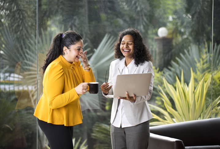 Two happy businesswomen with terrarium in the background.