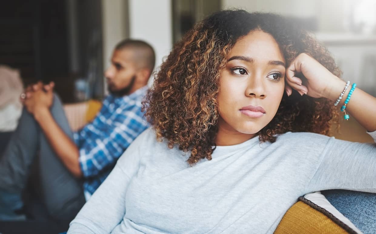 Young African American couple unhappy, angry and stressed couple sitting on a sofa together after arguing; they need empathy.