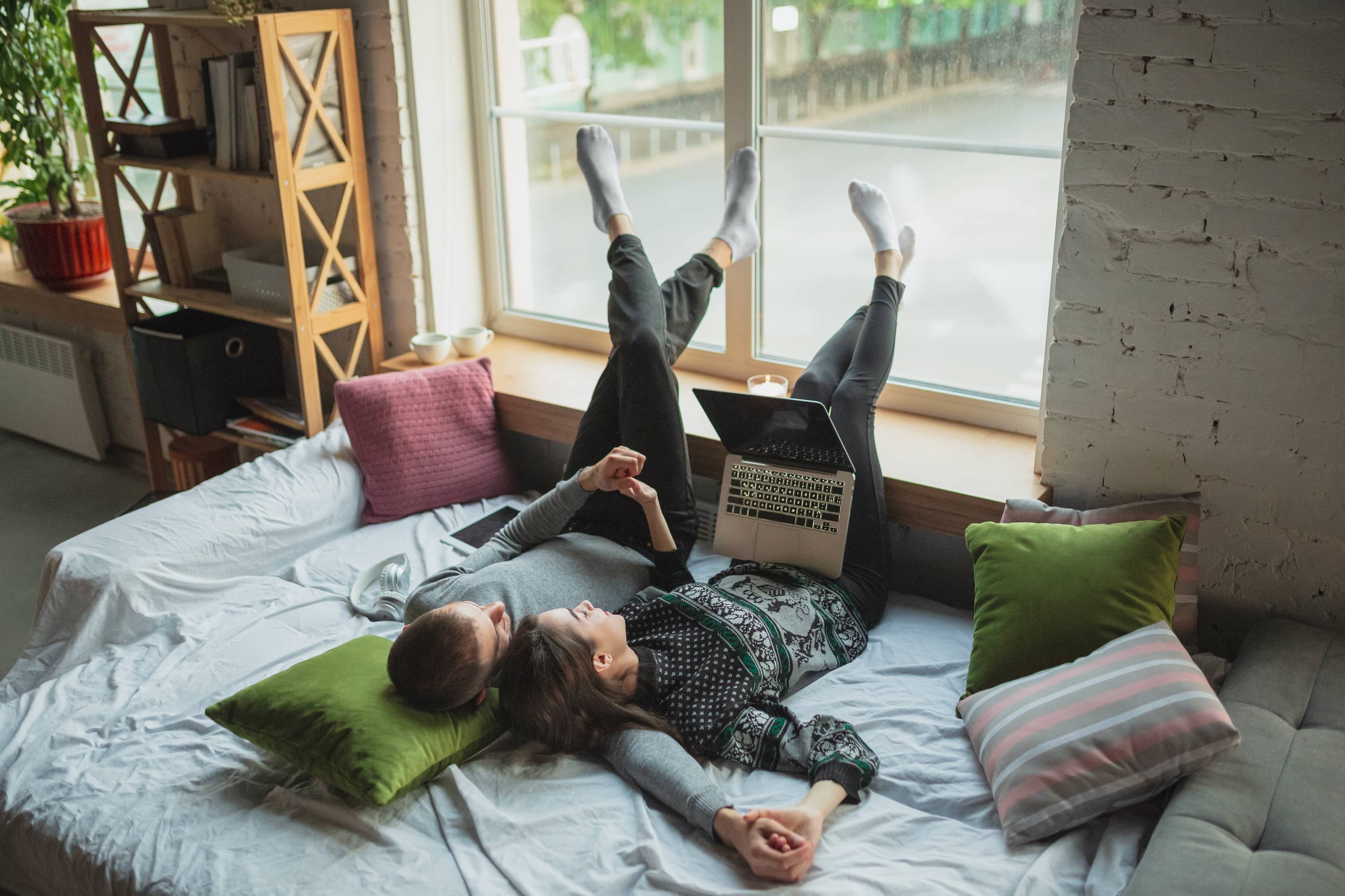 A happy young couple cuddling while watching a movie on their laptop.