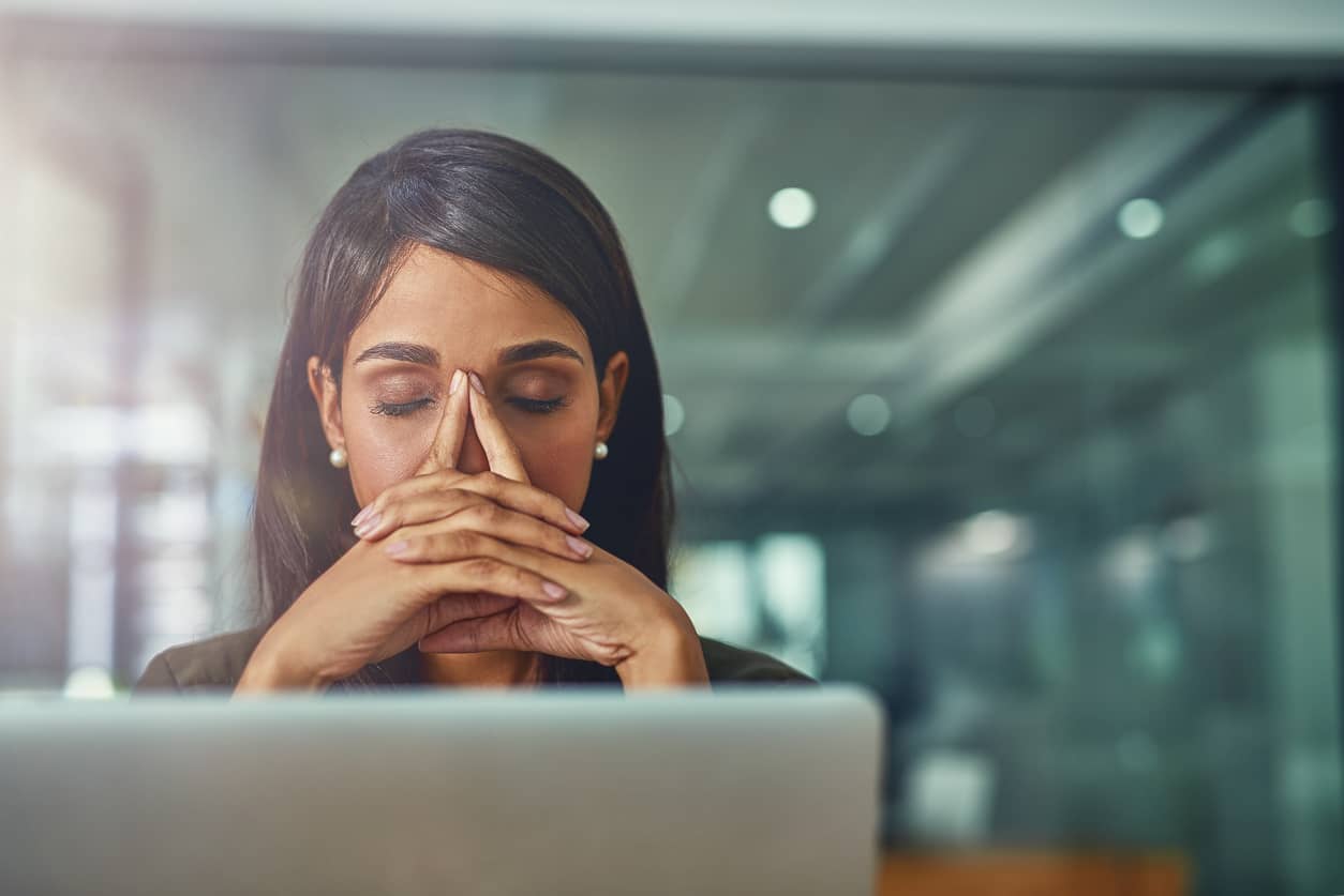 Woman overwhelmed and procrastinating her work on the computer.