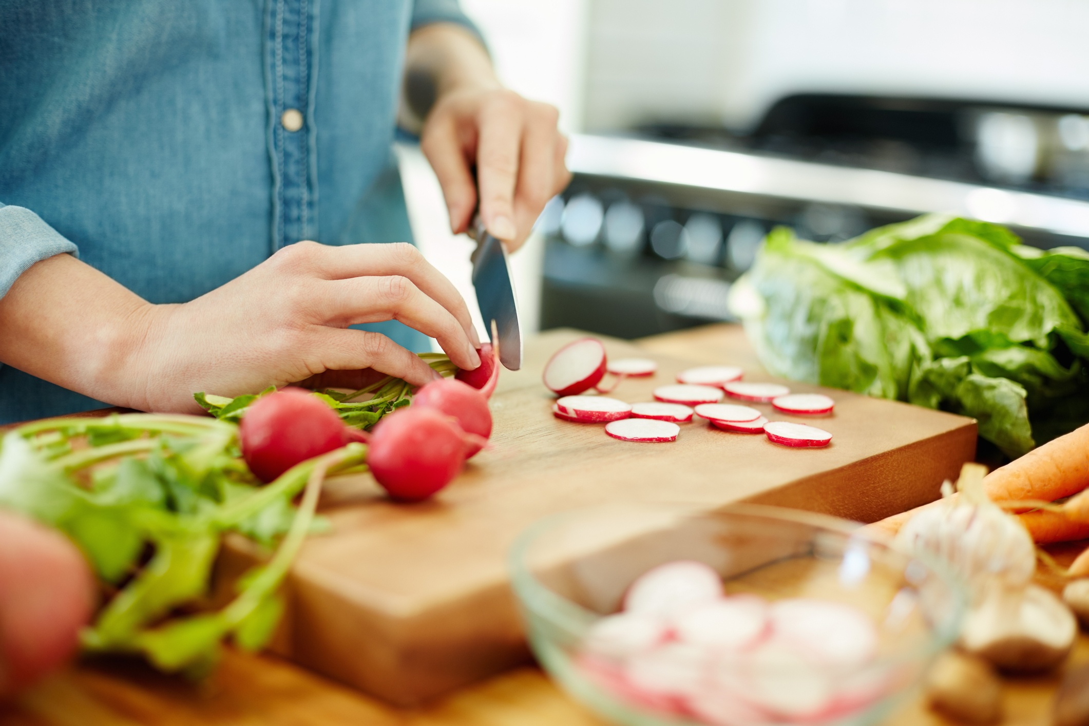 Woman chopping red radishes in the kitchen