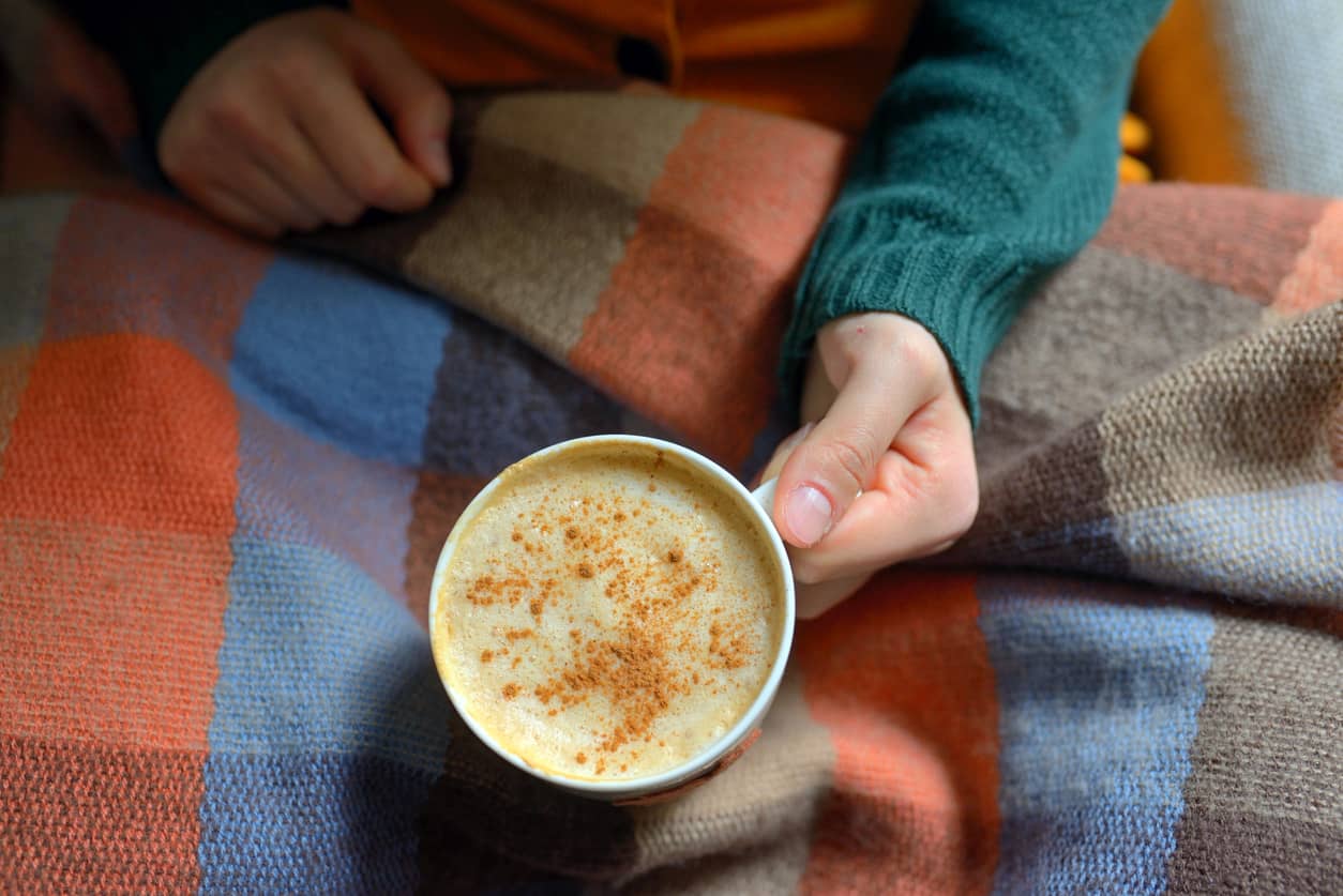 Woman sitting with a warm turmeric drink