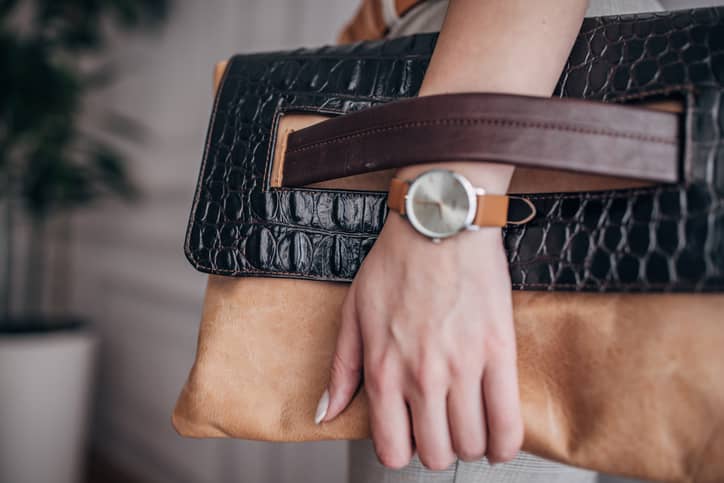 Woman holding a modern leather purse with an expensive watch on her wrist
