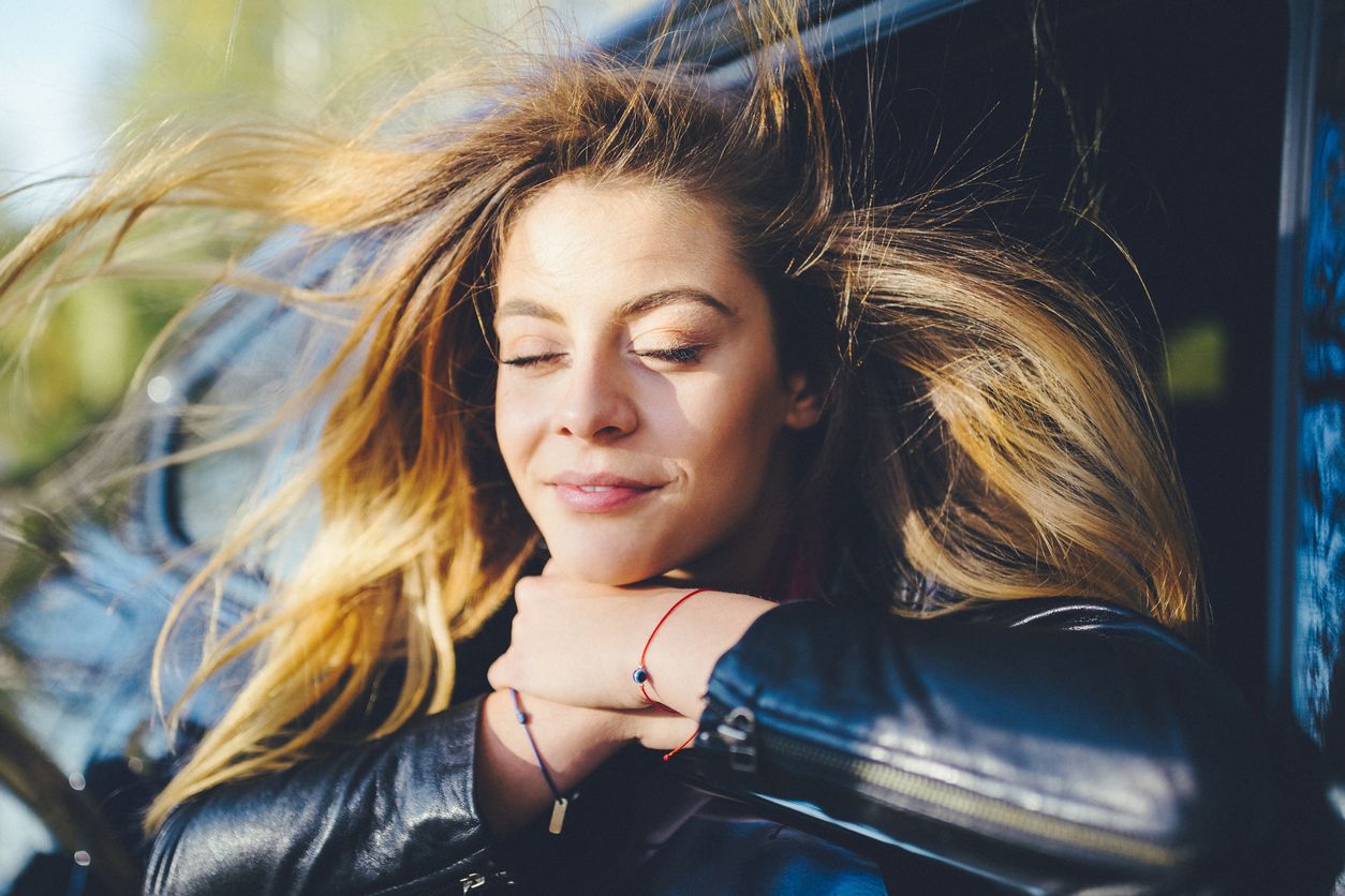 Woman on a road trip in car with breeze on her face as she visualizes her best life.