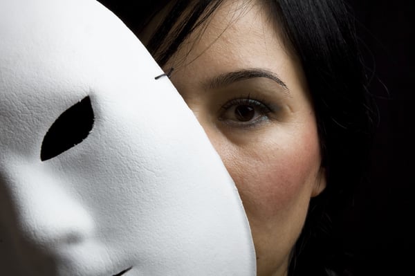 A woman taking off the mask of a people-pleaser