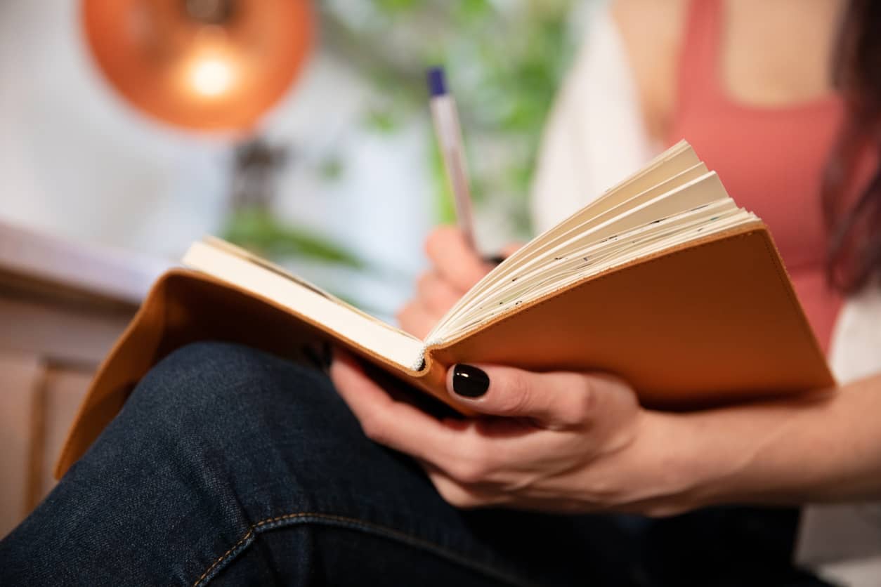 A woman journaling about her feelings to stop people-pleasing.