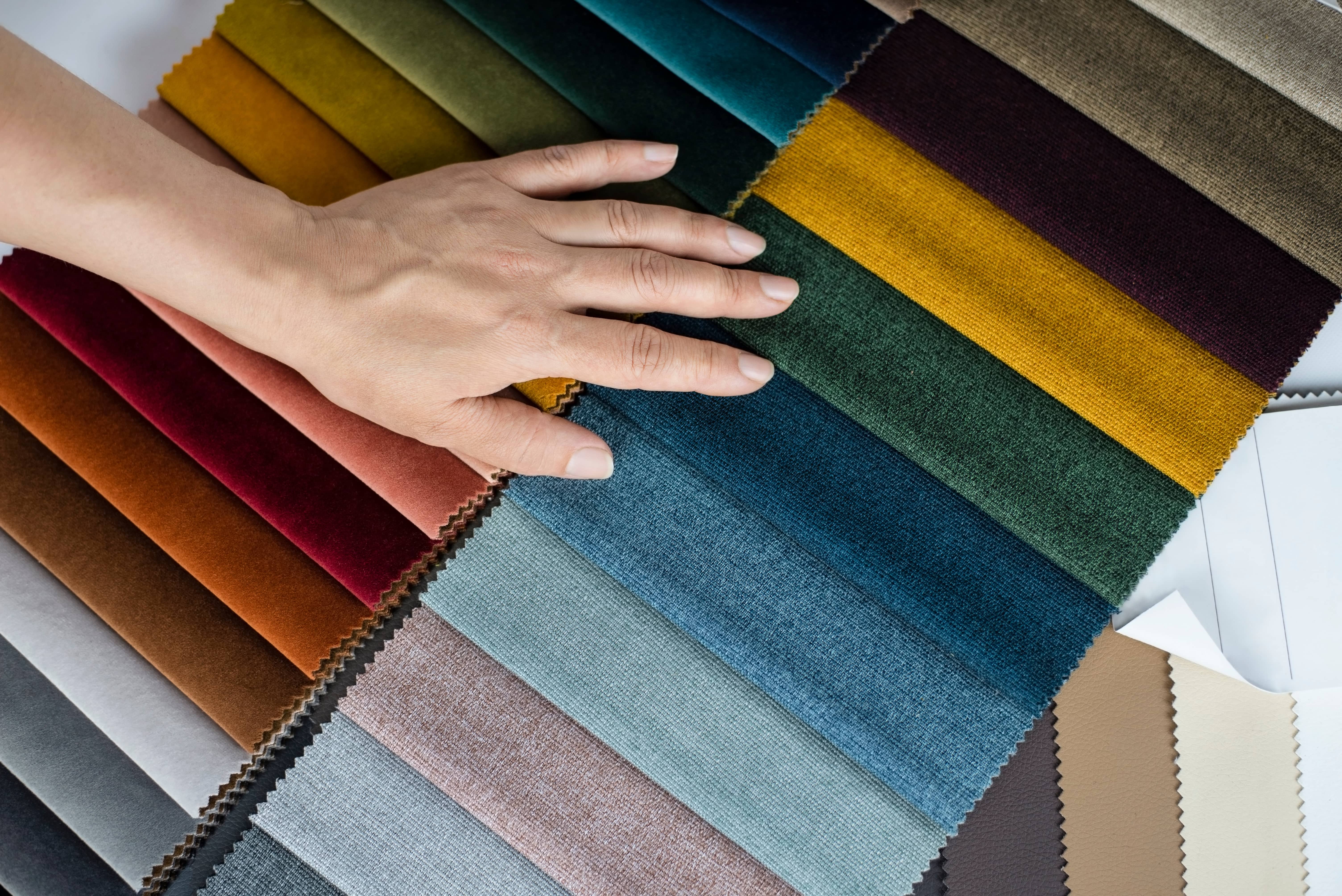 A woman's hand glazing over multi-colored fabrics.