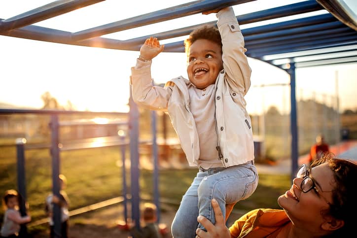 Happy toddler climbing a brachiation ladder at the park.