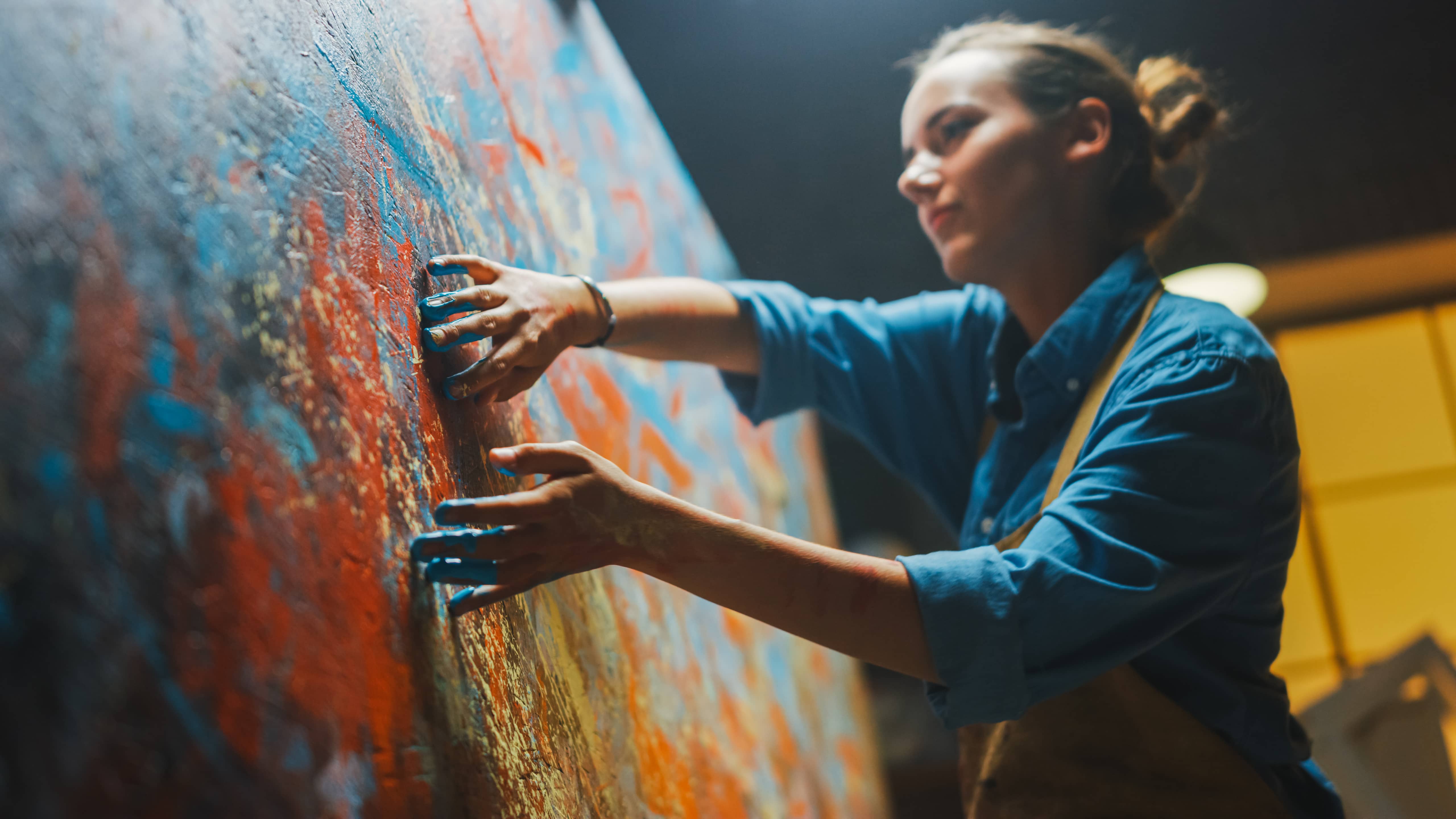 A young woman painting with her hands on a large canvas