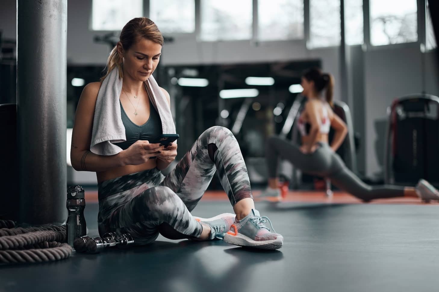 Young blonde woman on her phone after a workout in a gym.