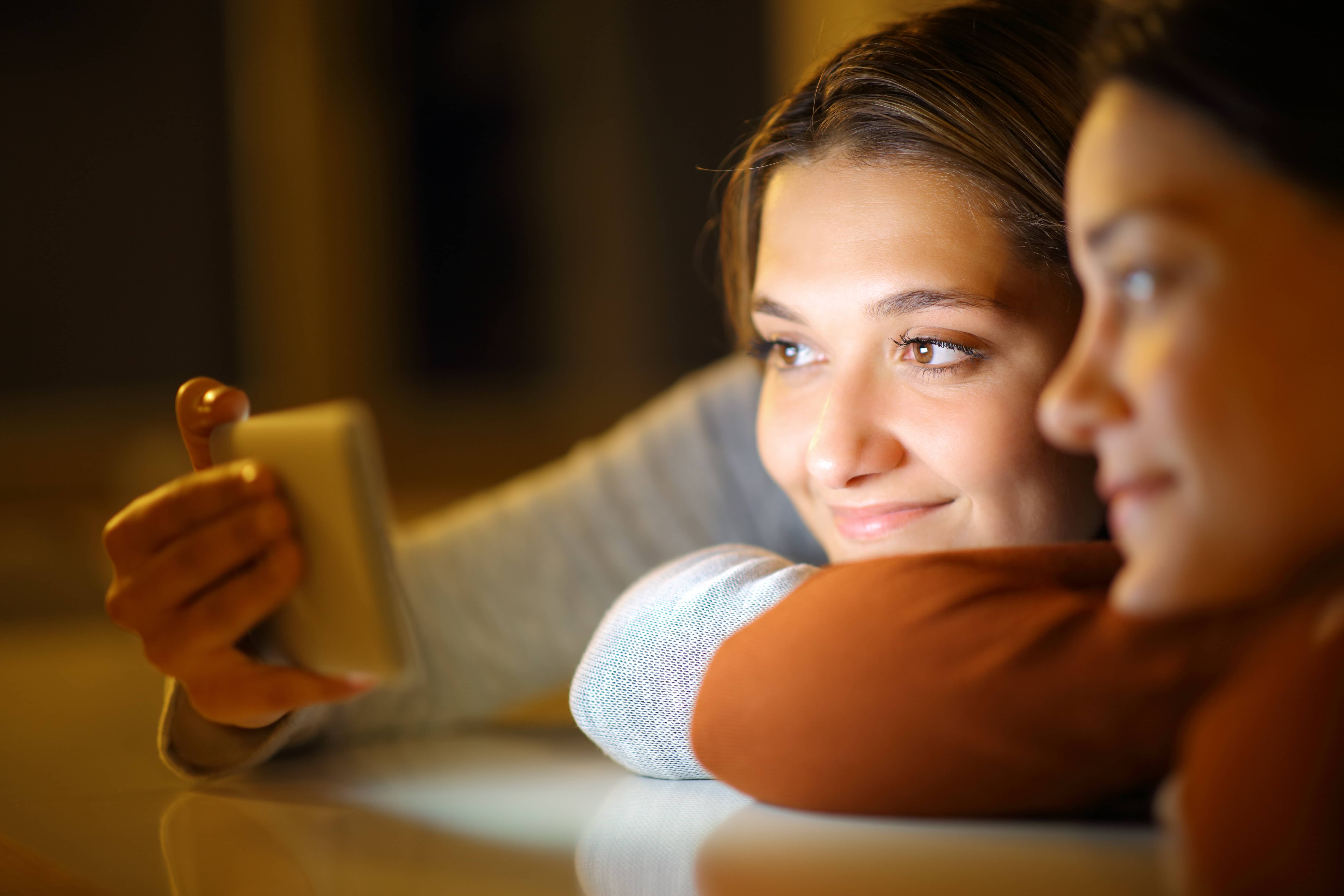 Teenage girls on their smartphones at bedtime.