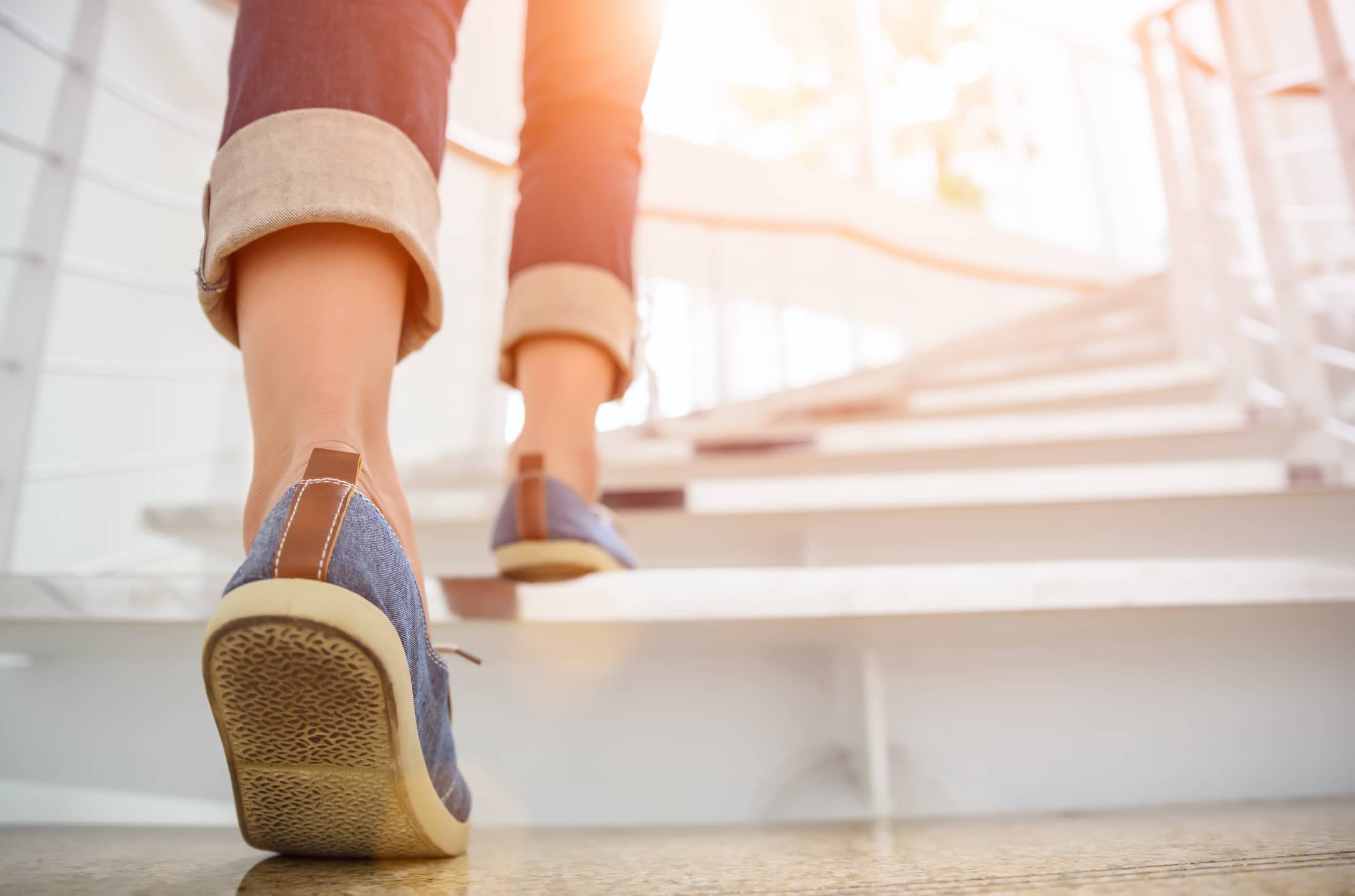 Young woman walking up stairs_rearview_AdobeStock_180667865 Small_Compressed