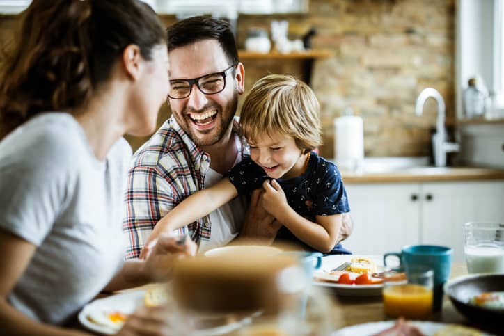 Young EQ family at breakfast laughing.