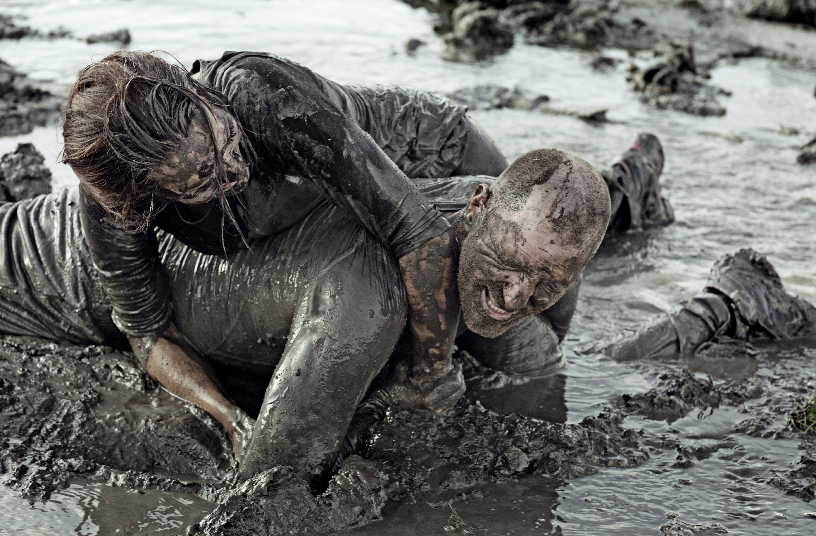 Young couple wrestling in the mud; relationship can be messy.