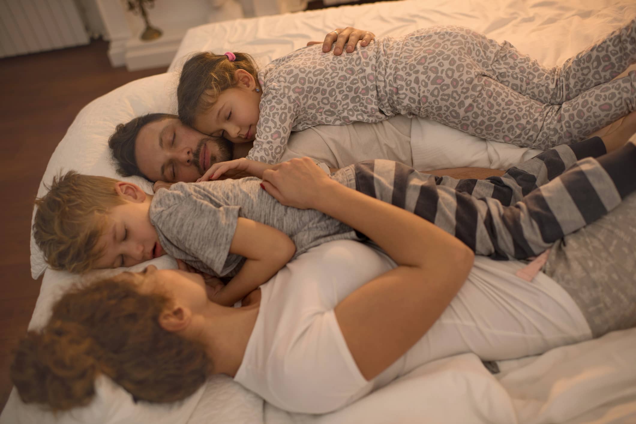 Young family taking a nap together on a bed