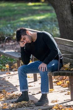 Young man on a park bench feeling sad and seeking resolution