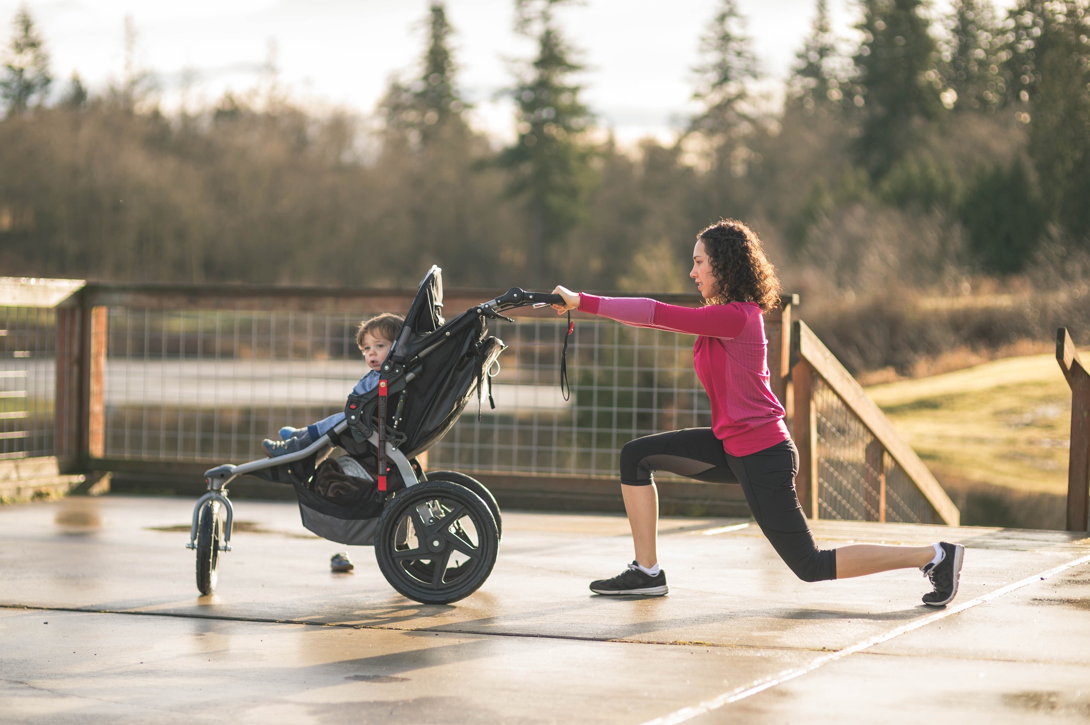 Young-mom-stretching-next-to-child-in-baby-stroller-647549370_2126x1415