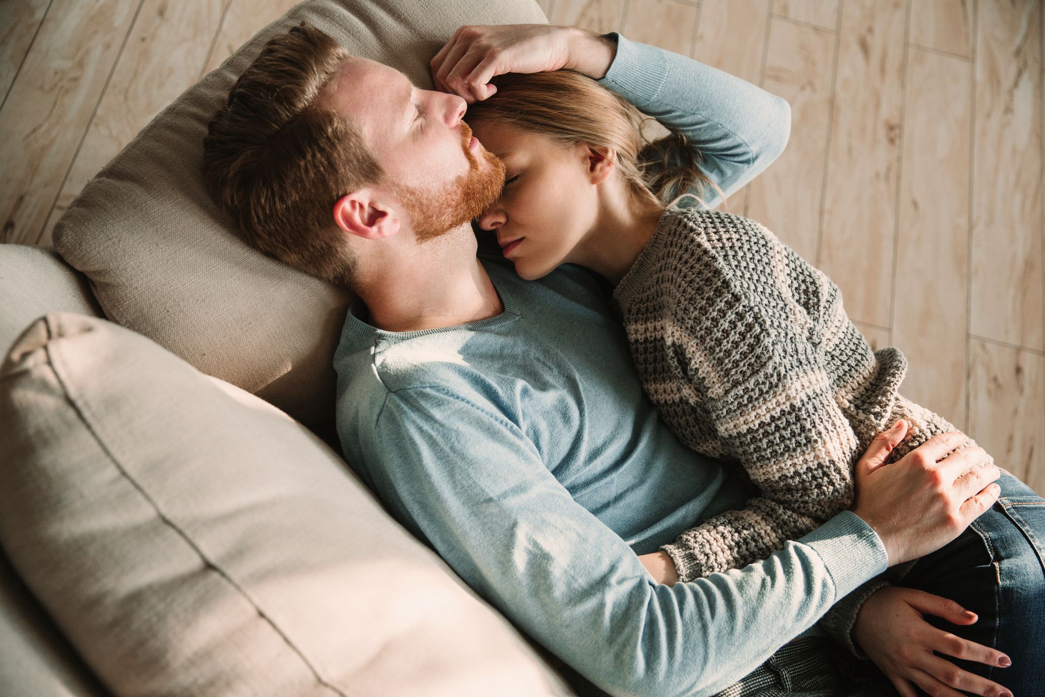 A young couple bonding and laying together on the couch