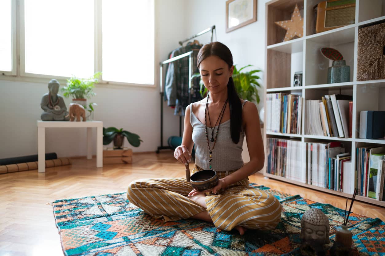 A young woman practicing meditation and mindfulness in her living room.