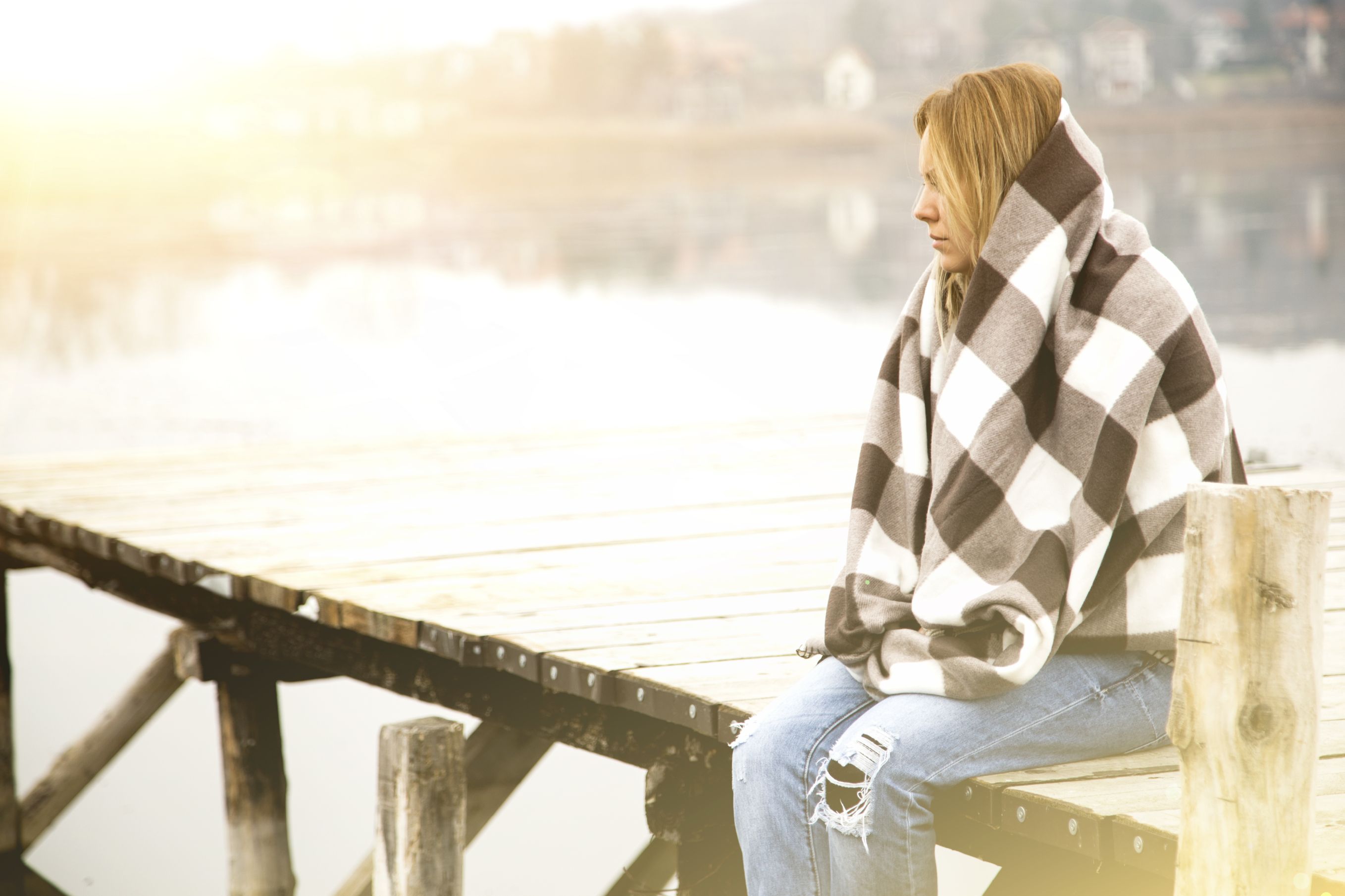 A young woman feels sadness as she sits on a dock