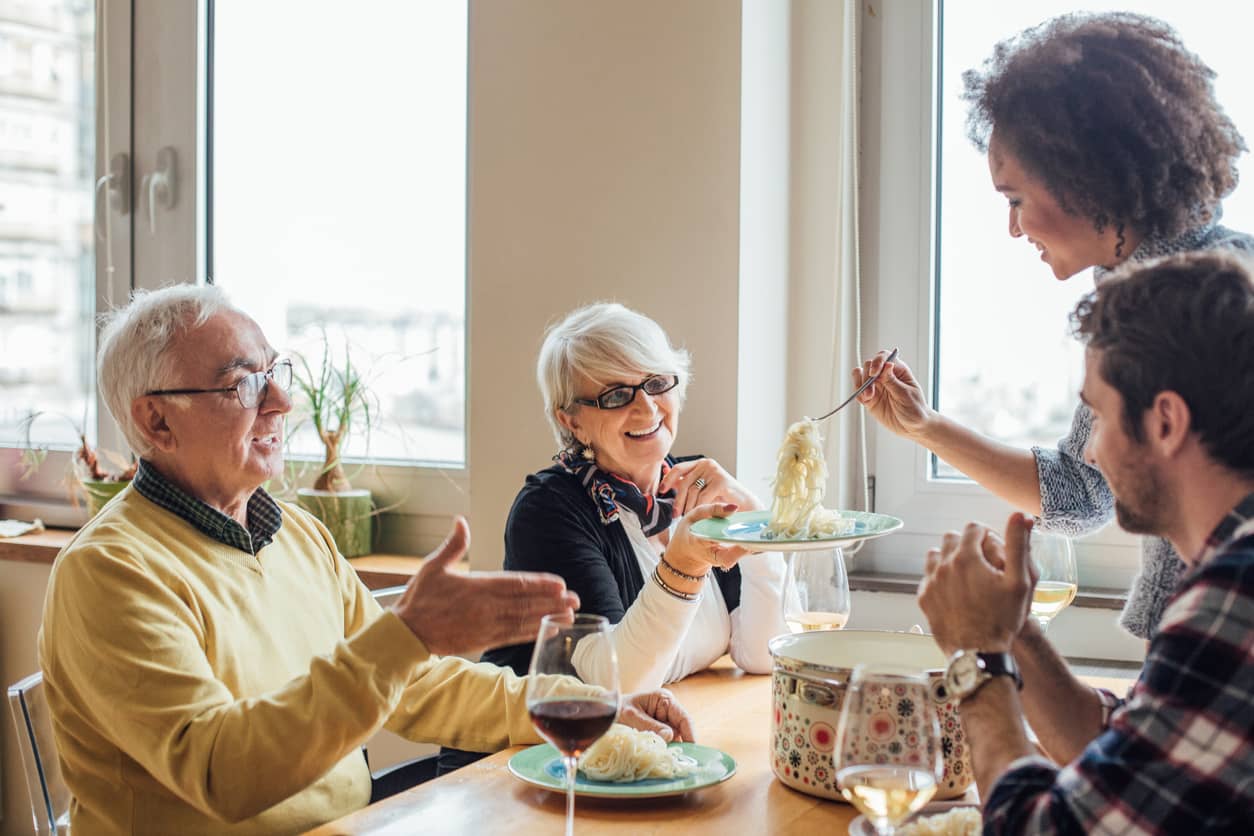 Young woman serving spaghetti to her family