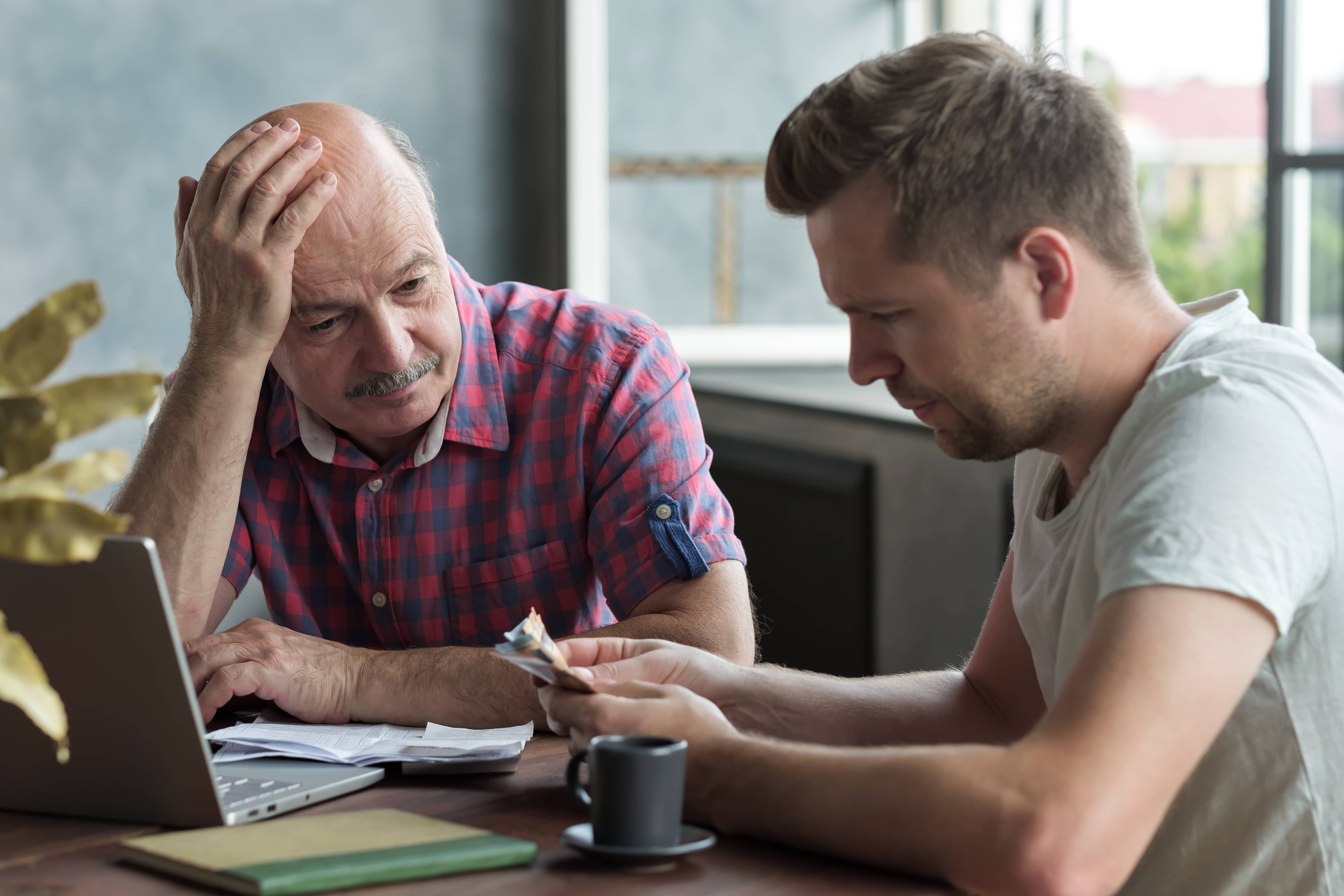 A father and his adult son budgeting money for back taxes.