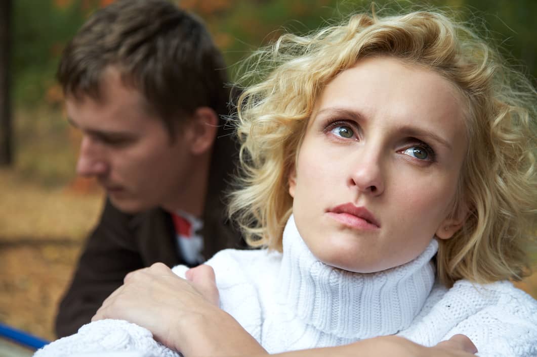 A woman turn away from her husband with a sad look on her face wondering if she's falling out of love.