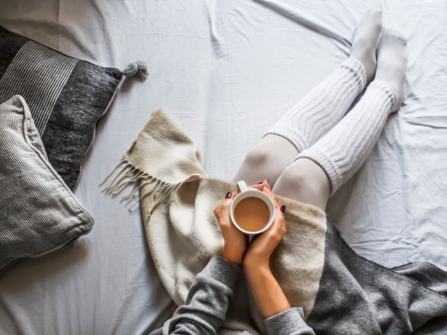 A young woman holding a cup of coffee contemplating